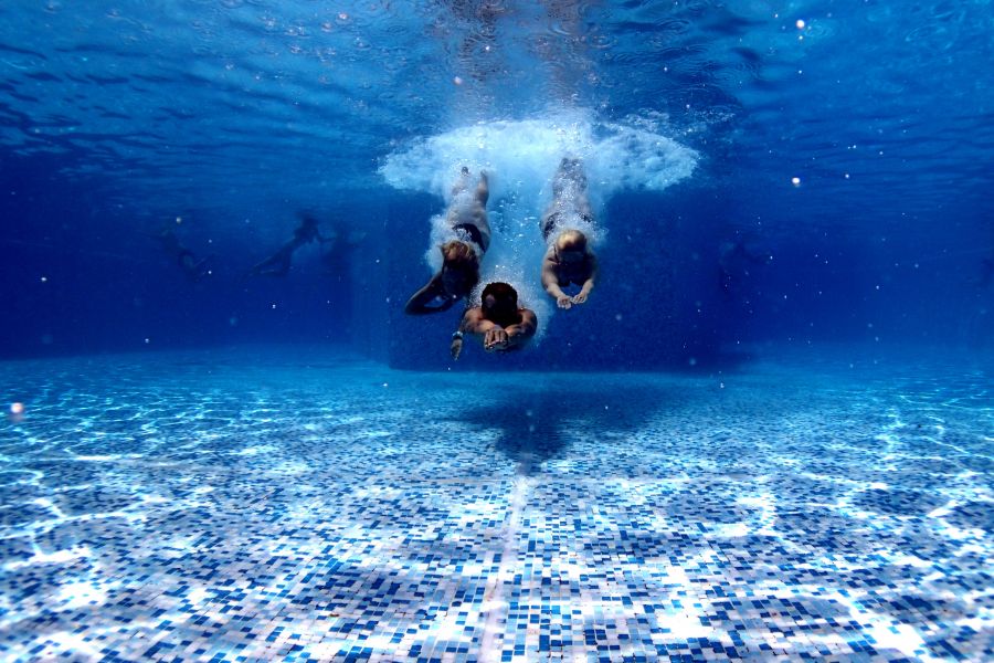 Fotografía de un grupo de deportistas sumergiéndose en piscina durante el curso de natación